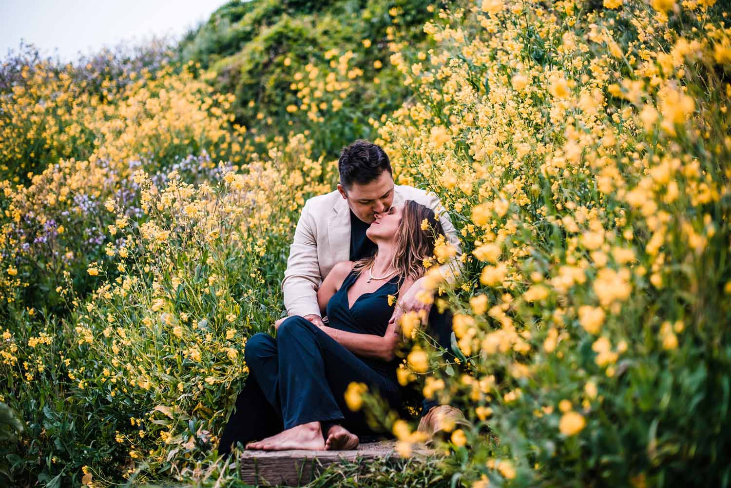 Couple on their elopement day at a state park in Big Sur soaking up the sunshine while embracing each other among a sea of yellow wildflowers 