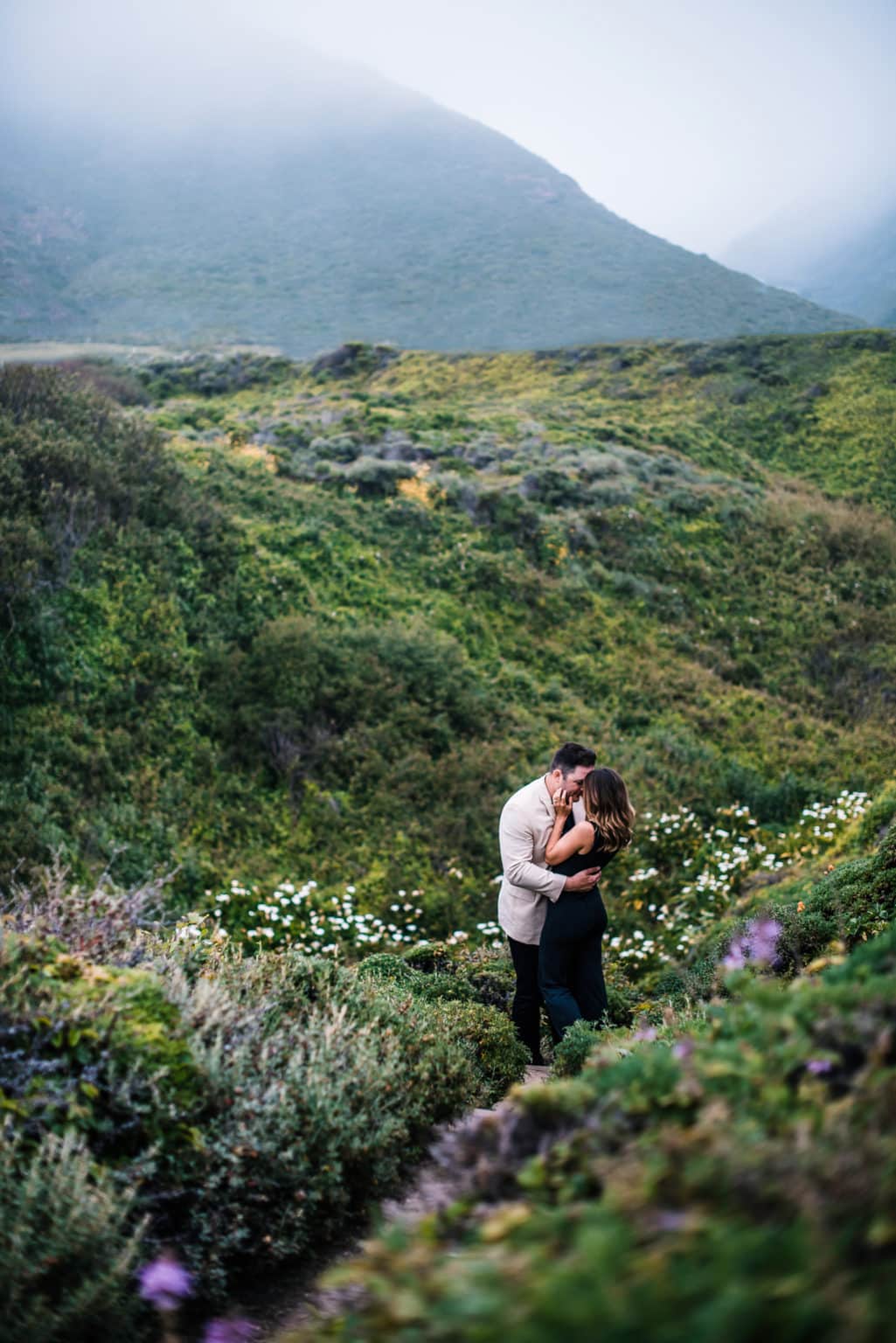 newly eloped couple kissing in the wild grass and shrubs of a private park in California