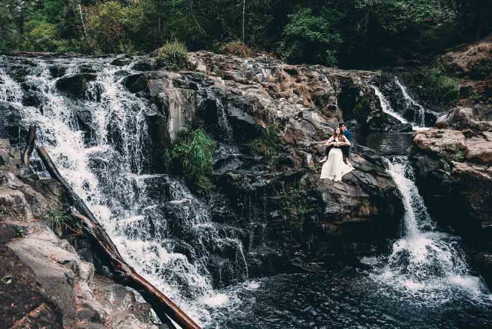 A couple sitting on rocks by a waterfall