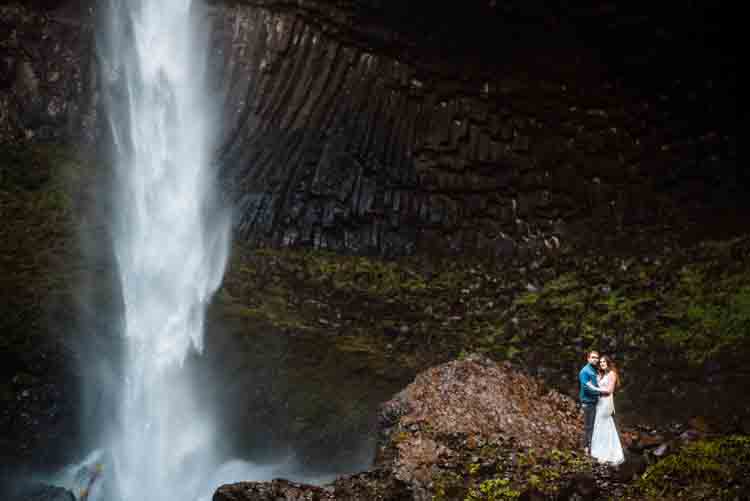 A couple being photographed with a waterfall in the background