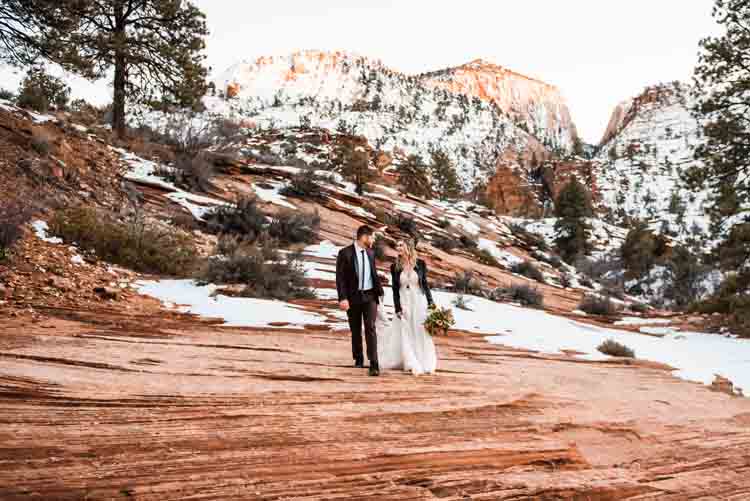 A bride and groom walking on a rocky mountain
