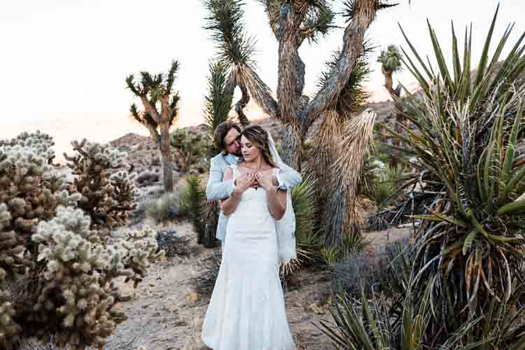 A bride and groom being photographed in the desert