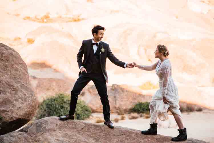 A bride and groom walking on a rocky mountain