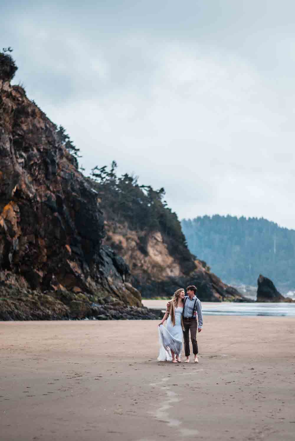 A couple on a beach coast with cliffs in the background