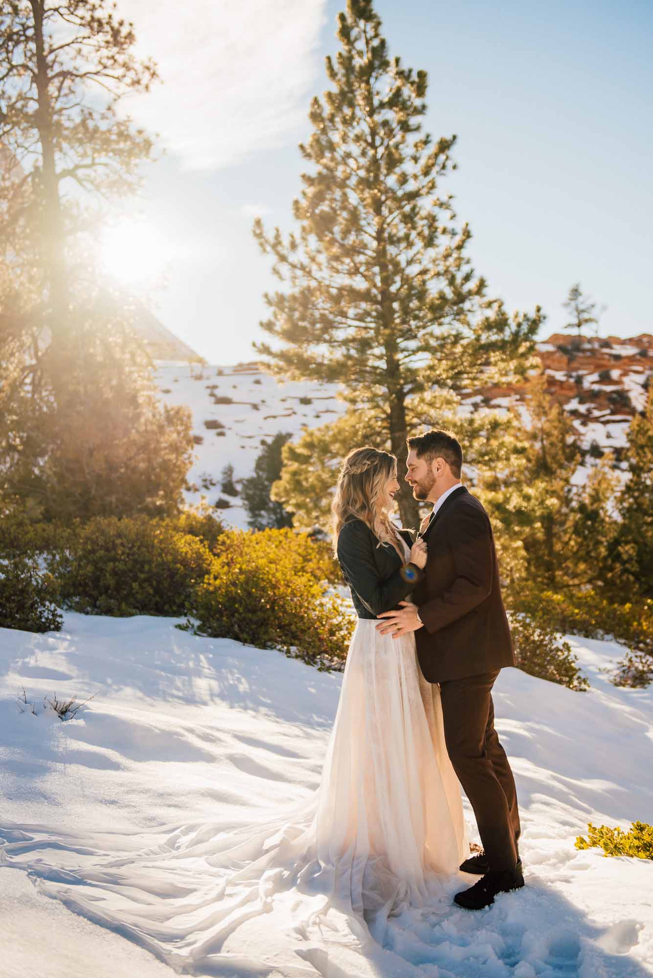 bride stands in a the perfect elopement dress while the sun behind her peeks through her veil 
