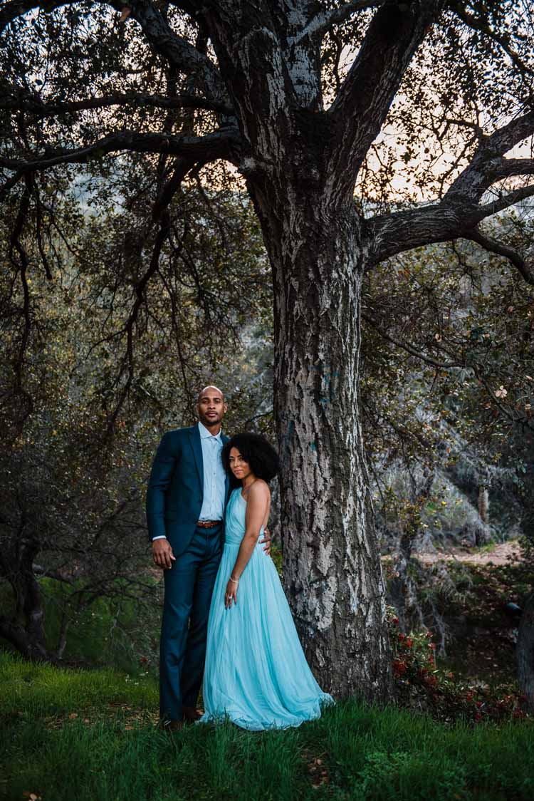bride standing with her groom in front of a tree in a beautiful blue elopement wedding dress