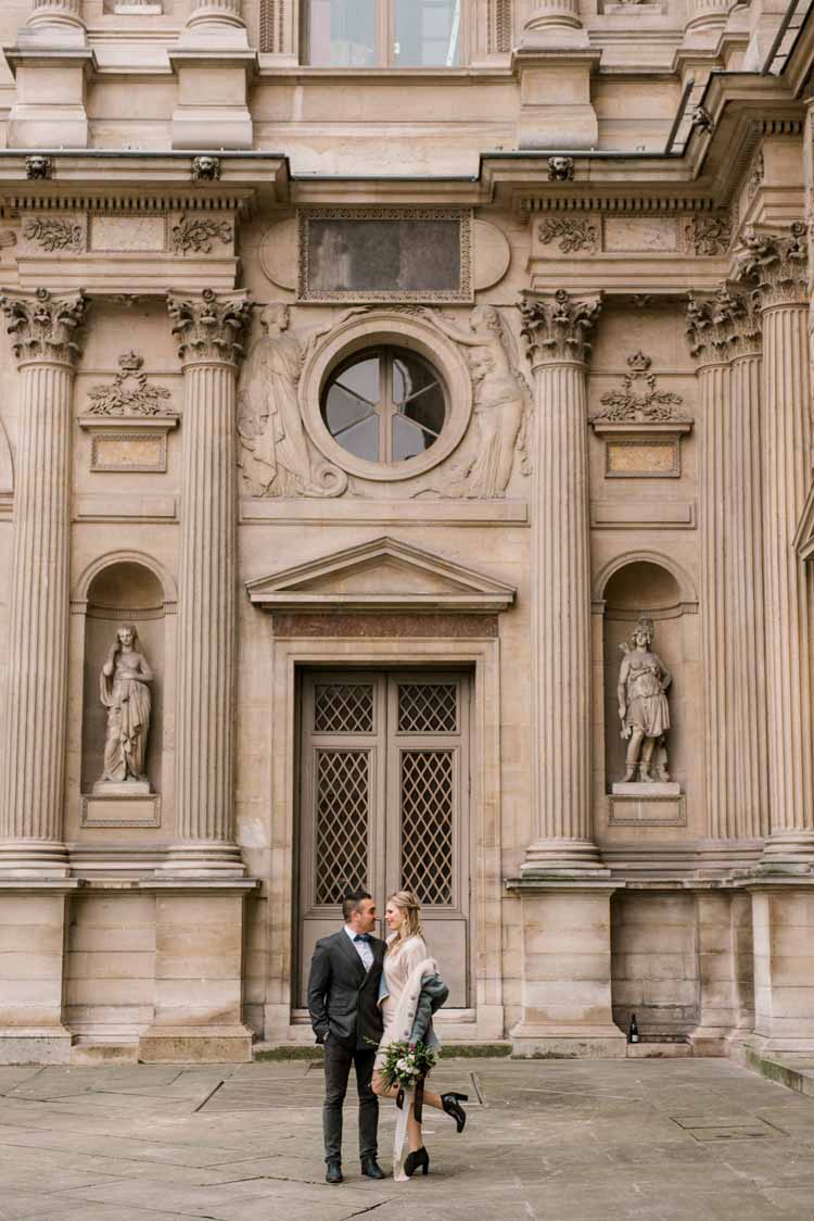 young couple gazes into each other's eyes in front of an old building for their Paris engagement photoshoot