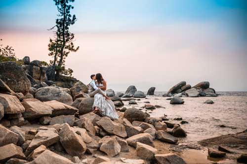 A couple sitting on rocks by the water during a lake tahoe elopement