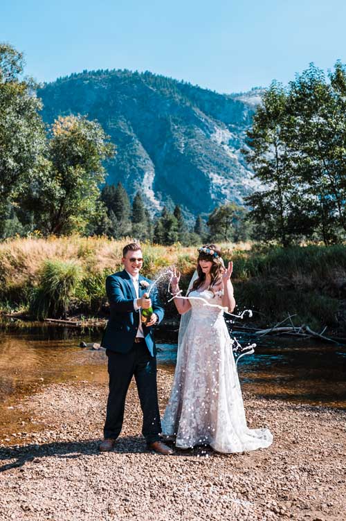 A groom popping champagne in front of his bride during an elopement in yosemite