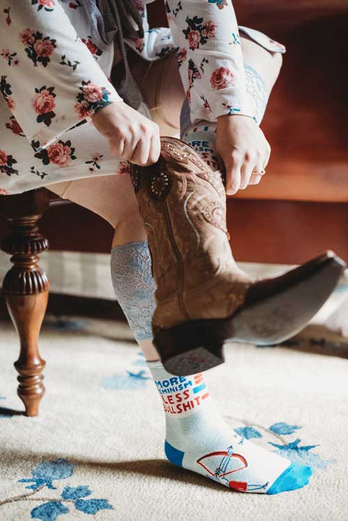 A bride putting on cowboy boots before an elopement