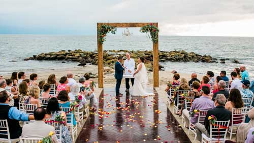 A bride and groom being married on the beach with family present during an elopement