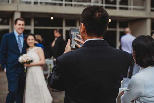 The father of a bride taking a picture of a bride and groom after an elopement