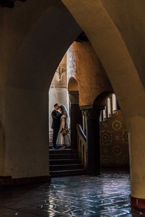 A groom kissing the forehead of a bride on the steps inside a church during an elopement