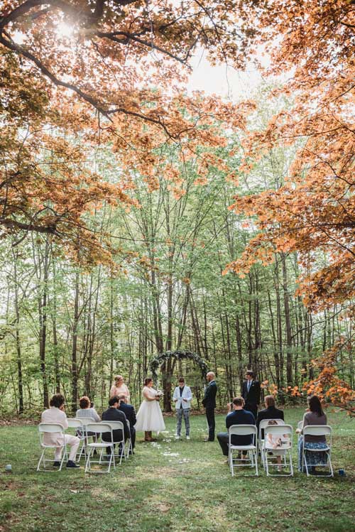 A bride and groom getting married during an elopement in the forest with trees all around