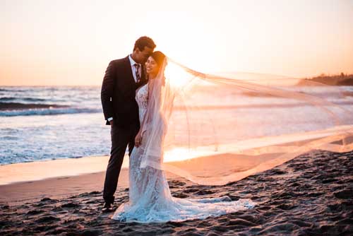 A bride and groom embracing each other during a sunset elopement on the beach