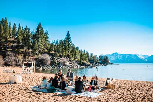 A group having a picnic while on the lake tahoe shore during an elopement