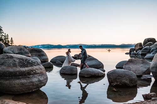 A couple stepping on rocks on the shore of lake tahoe during an elopement