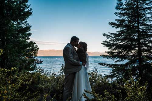 A couple kissing during an elopement surrounded by trees with lake tahoe in the background