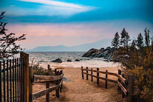 A path going to the water of lake tahoe with blue and purple skies during an elopement