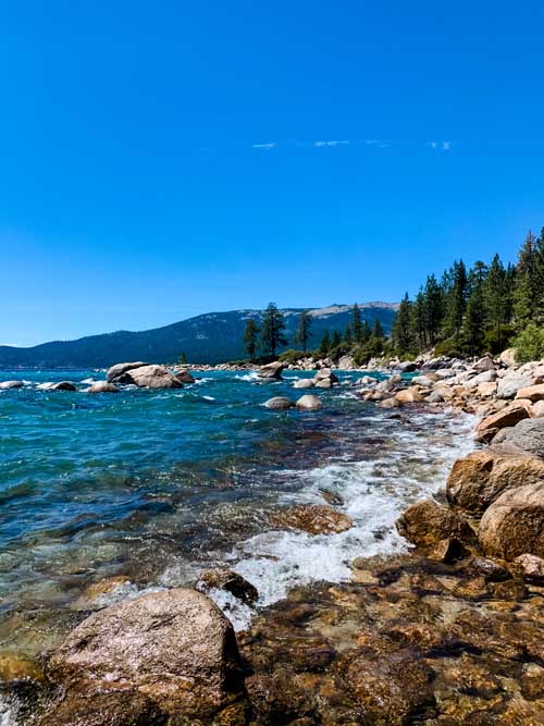 Waves crashing on the rocky lake tahoe shore during an elopement