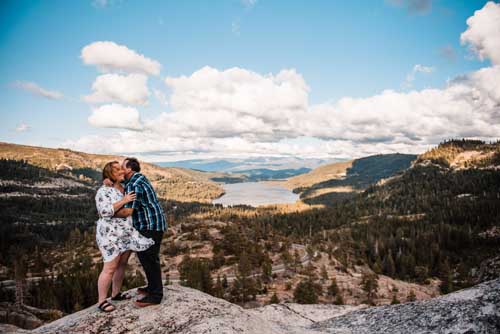 A couple kissing during an elopement on top of a cliff with lake tahoe in the distance