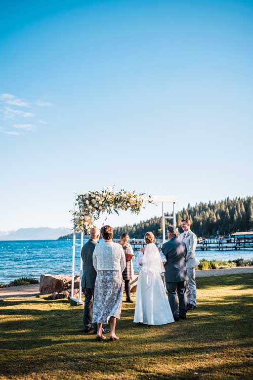 A couple being married during an elopement with family standing by and lake tahoe in the background
